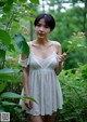 A woman in a white dress standing in the woods.