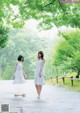 Two women in white dresses walking down a road.