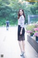 A woman in a white shirt and black lace skirt posing for a picture.