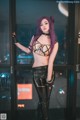 A woman with purple hair standing in front of a glass door.