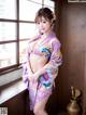 A woman in a purple kimono posing by a window.