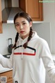 a woman wearing a white hoodie standing in a kitchen