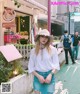 A woman in a white shirt and blue denim skirt standing on a sidewalk.