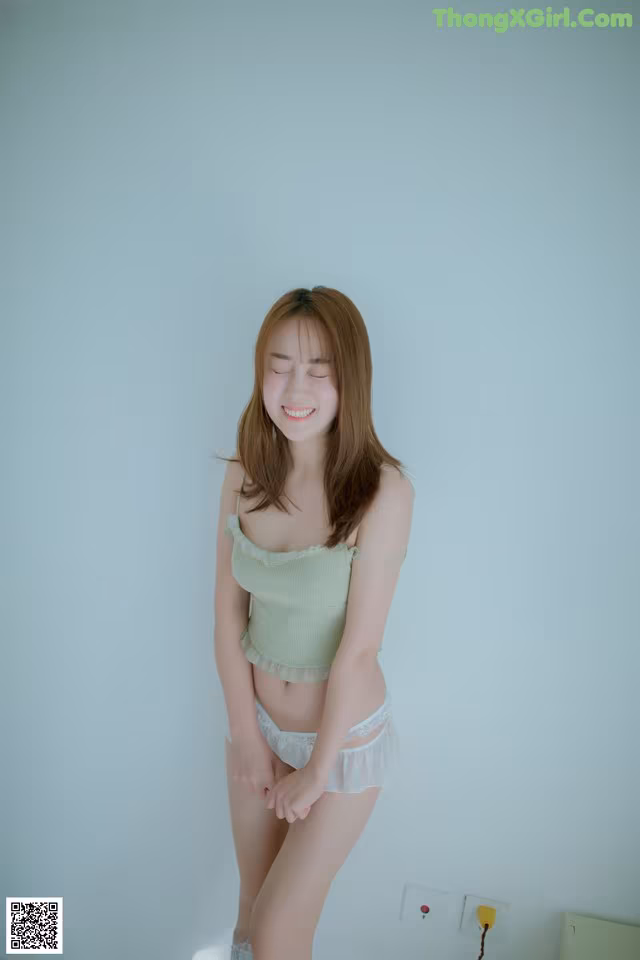 A woman in a green top and white panties posing for a picture.