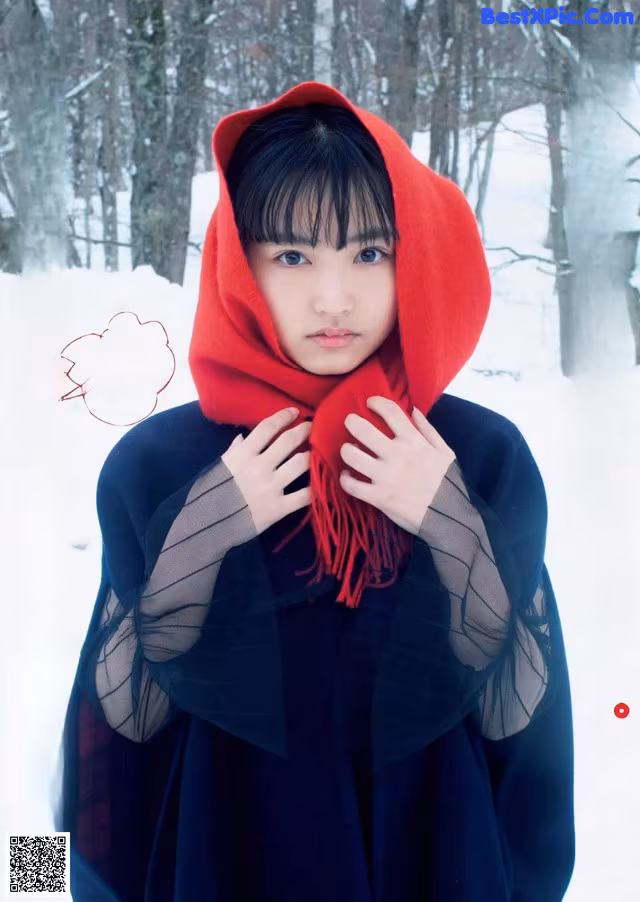 A woman in a red hooded cloak standing in the snow.