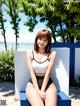 A woman in a white top and black shorts sitting on a blue chair.