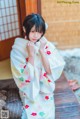 A woman in a kimono sitting on a wooden bench.