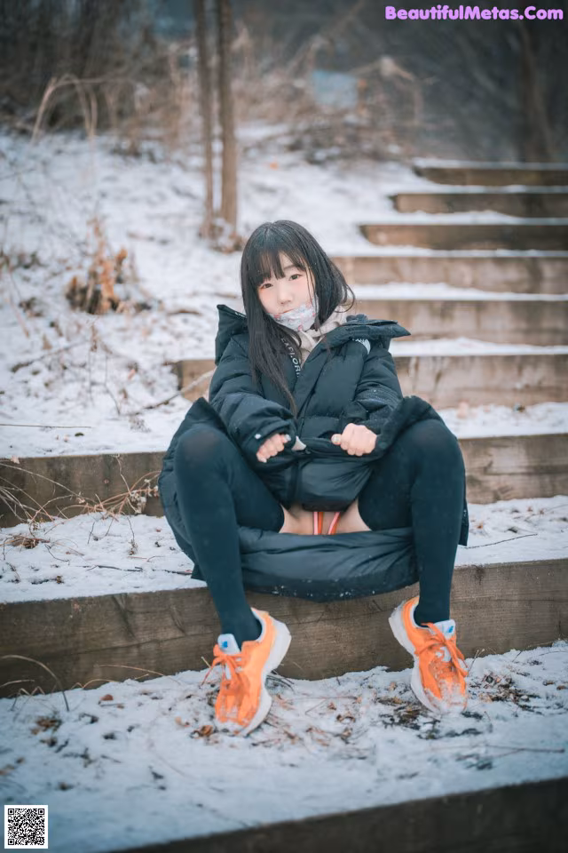 A woman sitting on some steps in the snow.