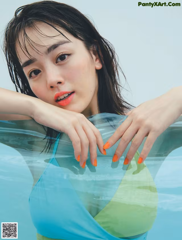 A woman in a blue and green bikini in the water.