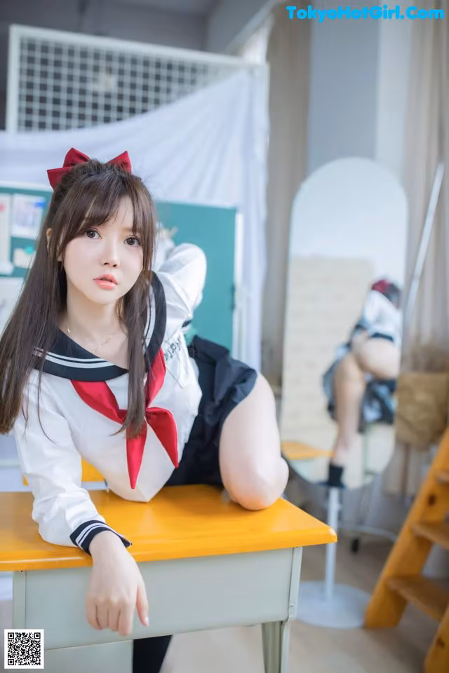 A woman in a school uniform sitting at a desk.