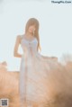 A woman in a white dress standing in a field.