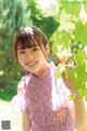 A young girl in a pink dress holding a green leaf.