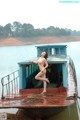 A naked woman standing on the back of a boat.