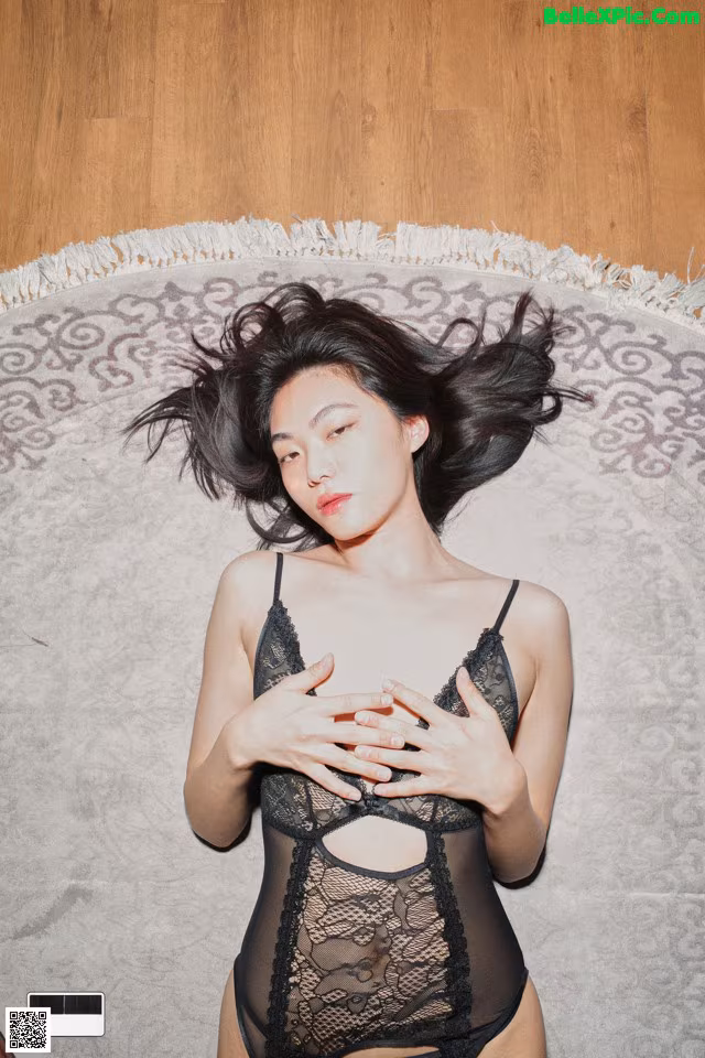 A woman laying on a rug with her hair blowing in the wind.