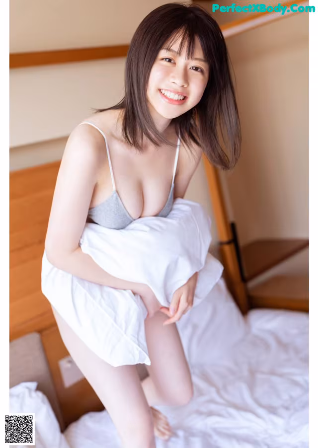 A woman sitting on top of a bed holding a pillow.